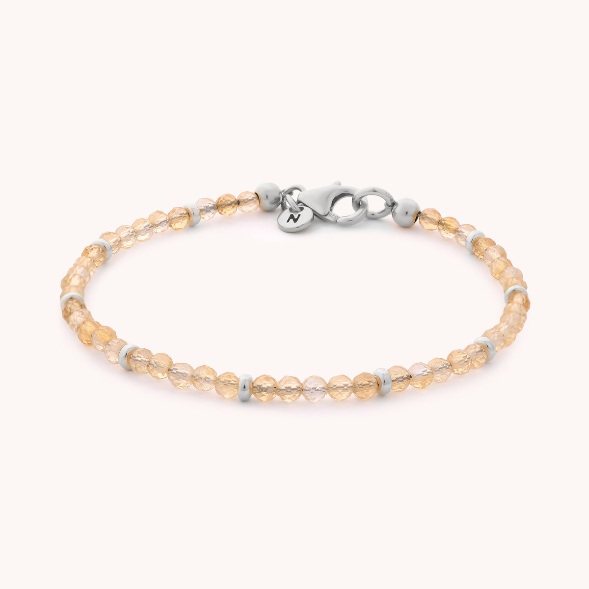 Citrine Orbit Bracelet - November: A delicate bracelet featuring small, round, faceted peach-colored beads with silver spacer accents and a silver lobster clasp, displayed on a simple light background—evocative of citrine and ideal as a November birthstone gift.