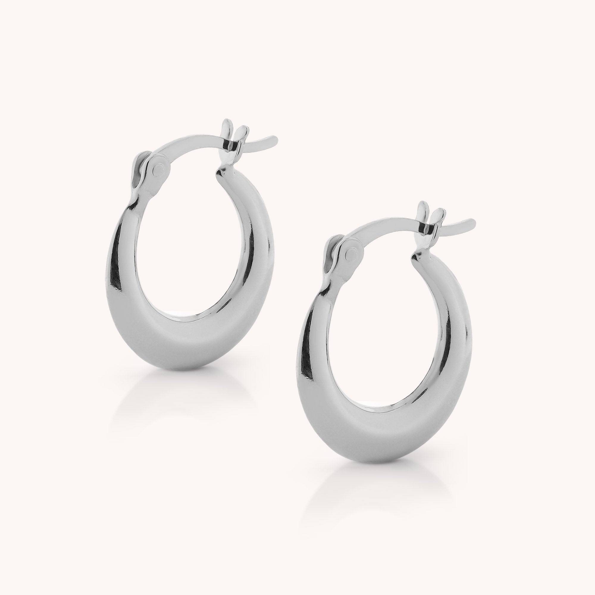 Contour Hoop Earrings—shiny, sculptural hoops crafted in sterling silver with secure latch-back closures, displayed against a plain, light background.
