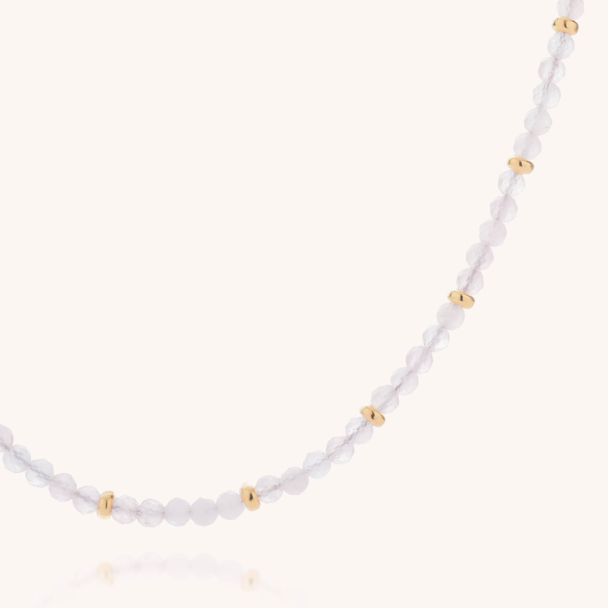 The Rose Quartz Orbit Necklace features small, round, faceted rose quartz beads paired with evenly spaced gold-plated eco sterling silver beads, elegantly displayed on a plain light background.