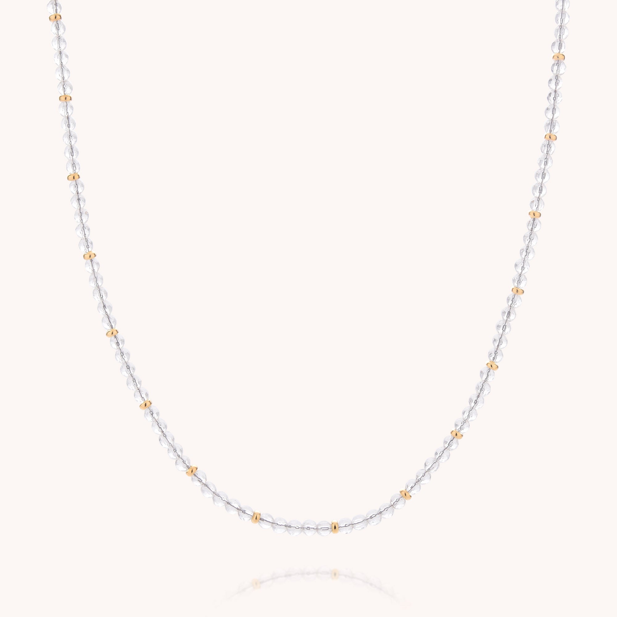Introducing the Clear Quartz April Birthstone Orbit Necklace: a delicate piece featuring alternating small silver and gold beads, beautifully accented with a sparkling clear quartz—the birthstone for April—elegantly displayed on a plain light background.
