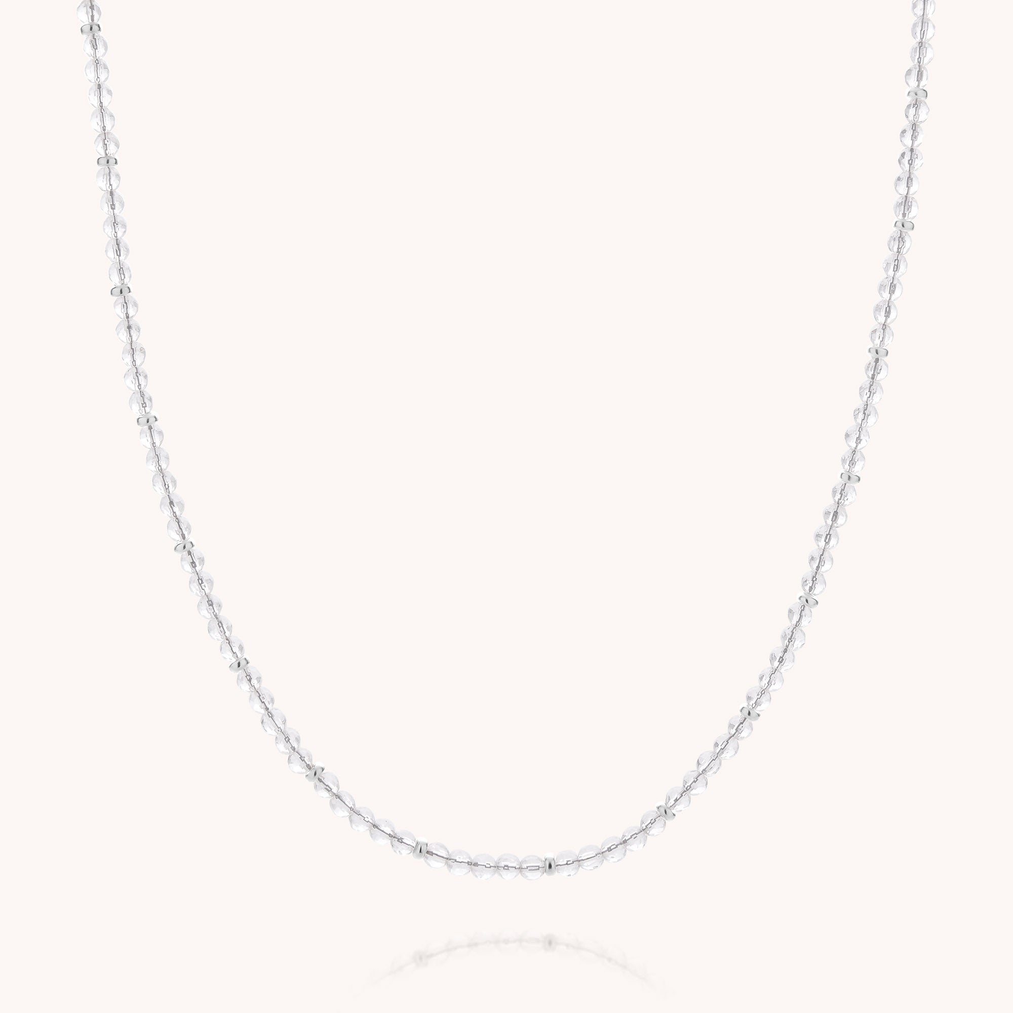 The Clear Quartz April Birthstone Orbit Necklace features a delicate silver beaded chain and a sparkling clear quartz gemstone, beautifully displayed against a plain, light background.
