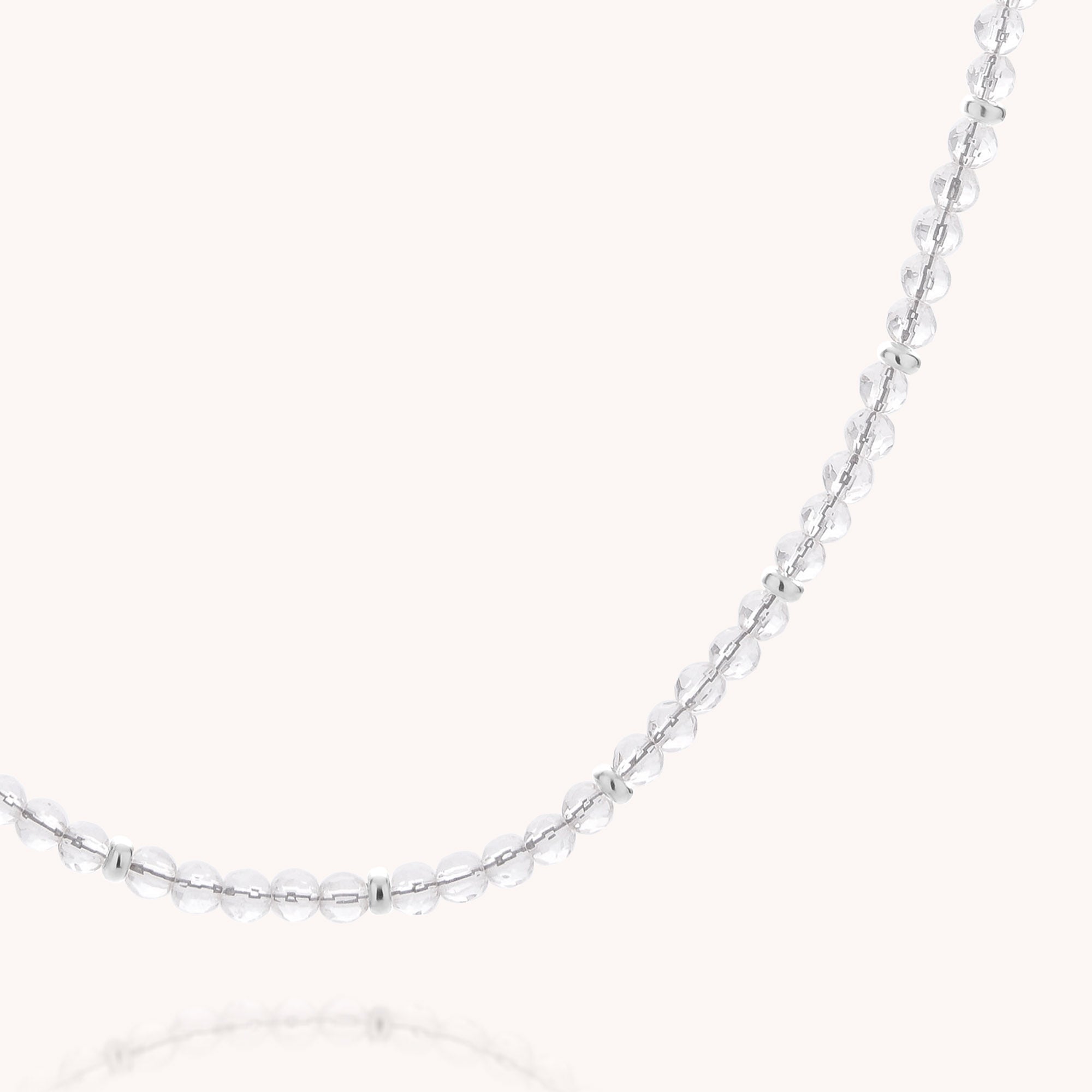 Introducing the Clear Quartz April Birthstone Orbit Necklace: a delicate silver accessory adorned with small, evenly spaced round clear quartz beads, elegantly displayed against a plain light background—an ideal gift for anyone celebrating an April birthday.