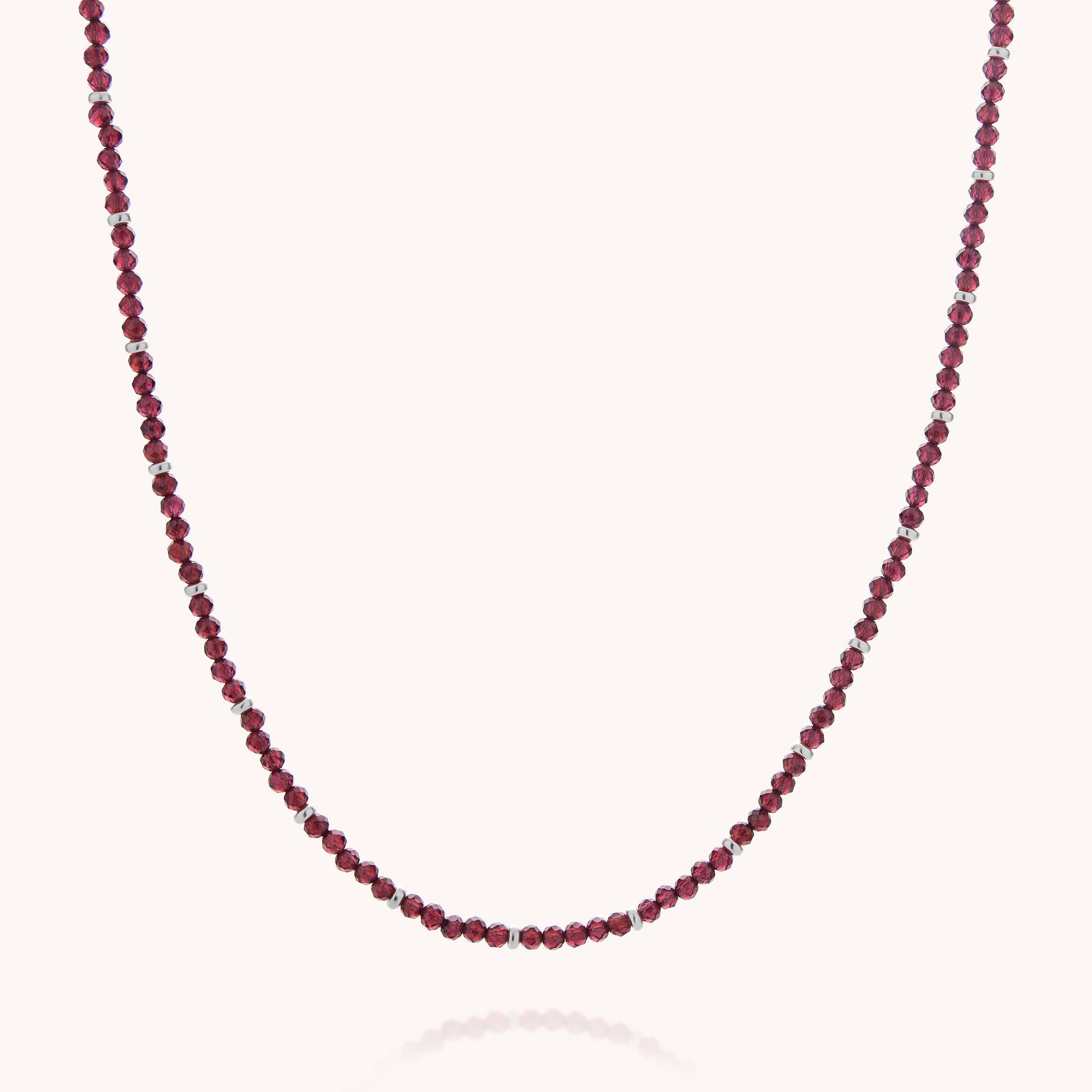 Introducing the Garnet Orbit Necklace: a delicate, handcrafted piece featuring small round garnet beads spaced evenly along a slender chain, beautifully displayed against a plain white background—perfect for adding subtle elegance to your everyday look.