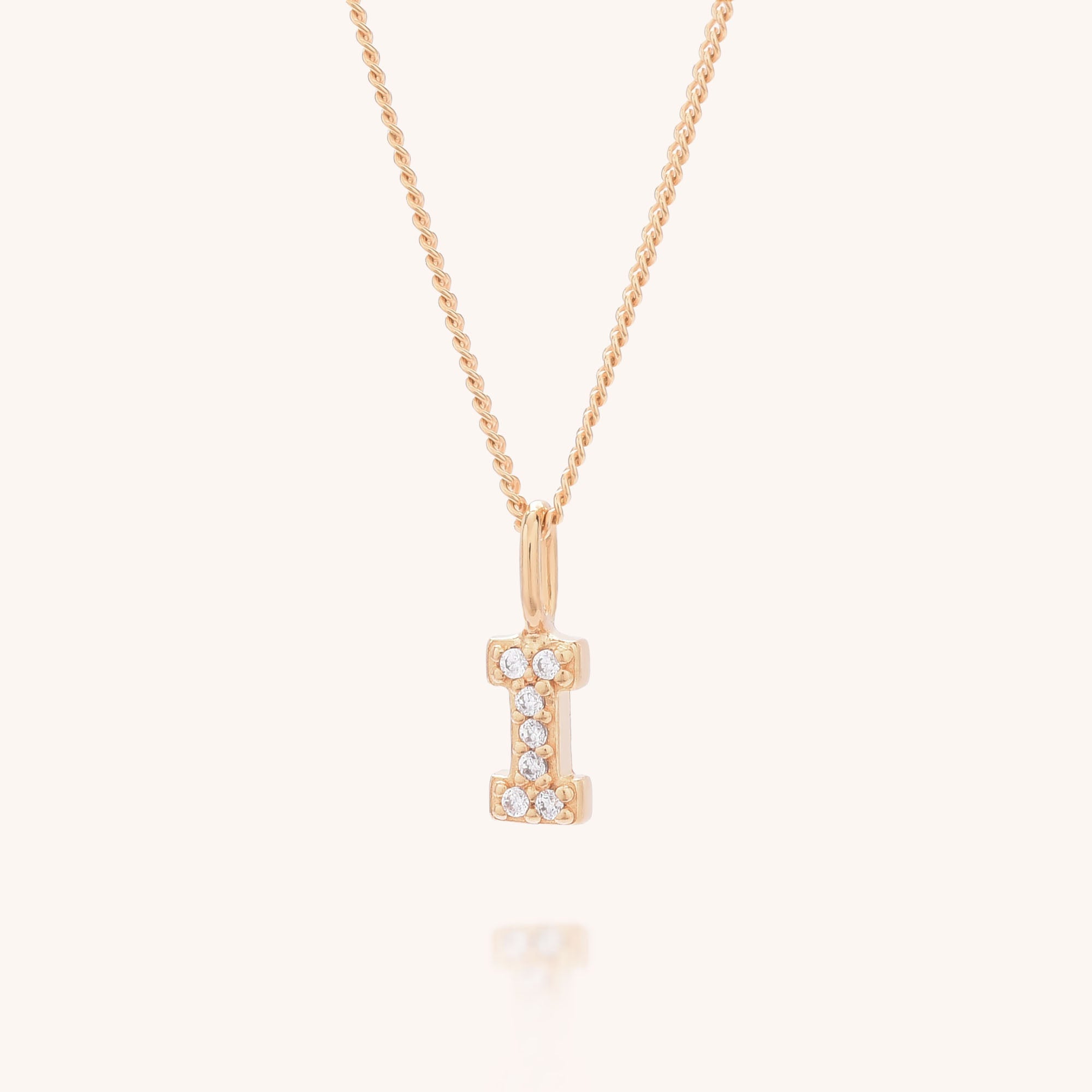 The Initial Sparkle Necklace showcases a gold &quot;I&quot; pendant with sparkling cubic zirconia, set against a light background—an ideal personalised accessory for any occasion.