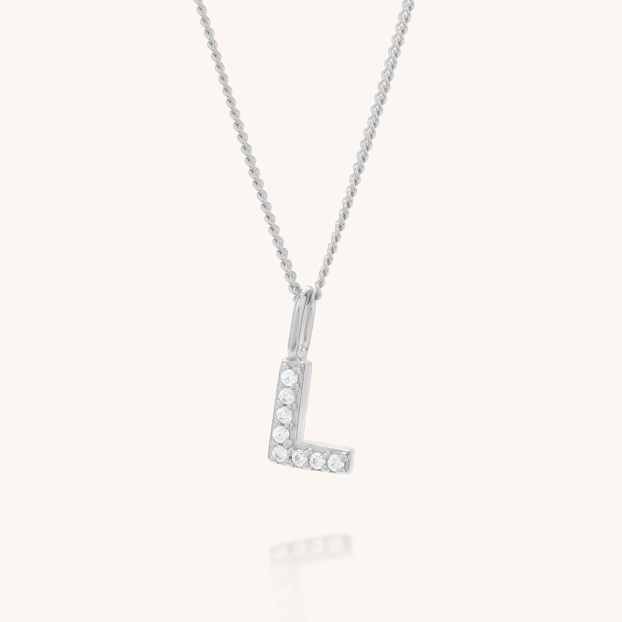 The Initial Sparkle Necklace showcases a silver &quot;L&quot; pendant embellished with cubic zirconia, set against a simple light background.