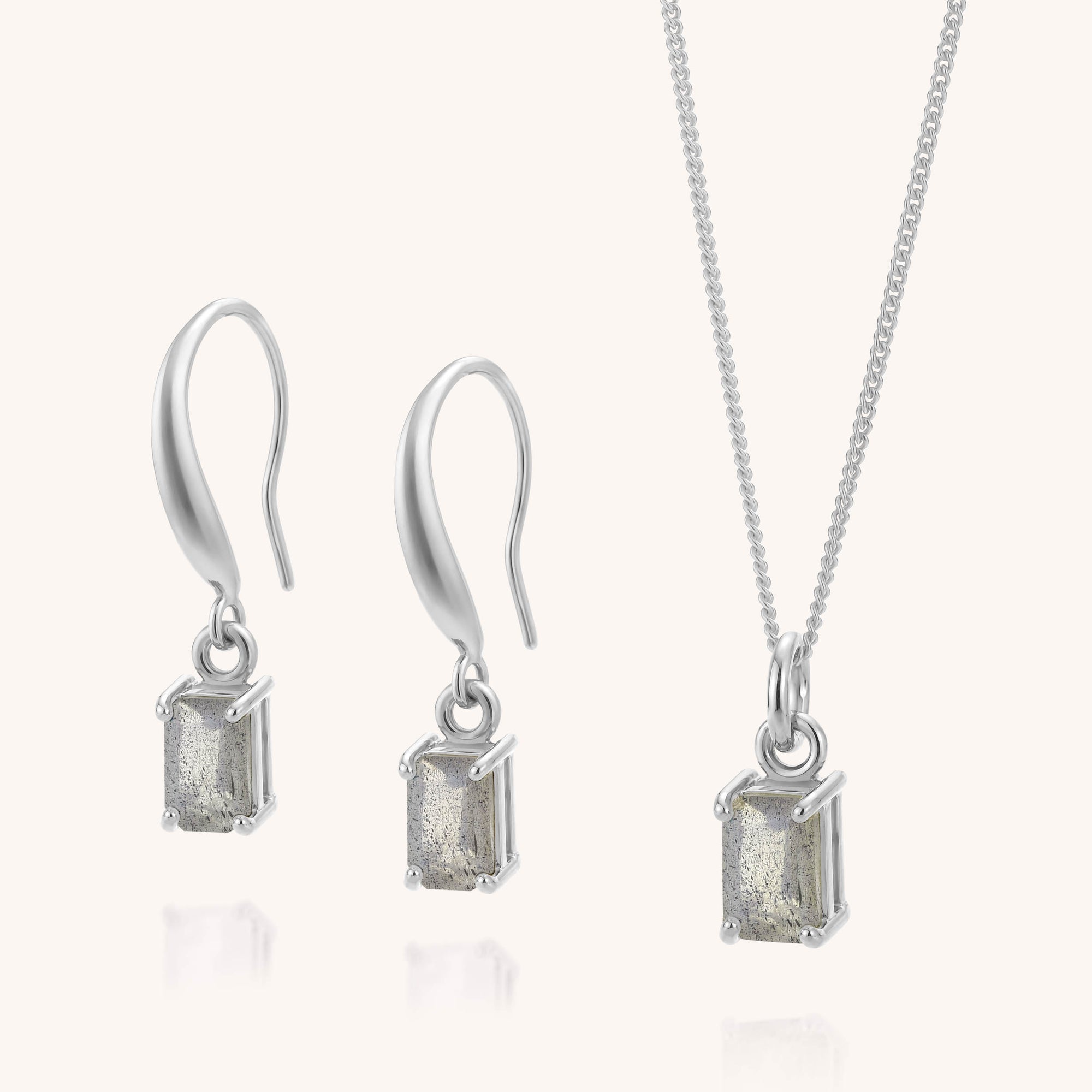 Introducing the Labradorite Octavia Necklace & Earrings Set—a coordinated jewelry ensemble featuring a sterling silver necklace and drop earrings, each adorned with a rectangular labradorite stone in a minimalist prong setting. The drop earrings are secured with hook fastenings, while the necklace hangs from a delicate chain. This elegant set is ideal for those who value refined sophistication and timeless style.