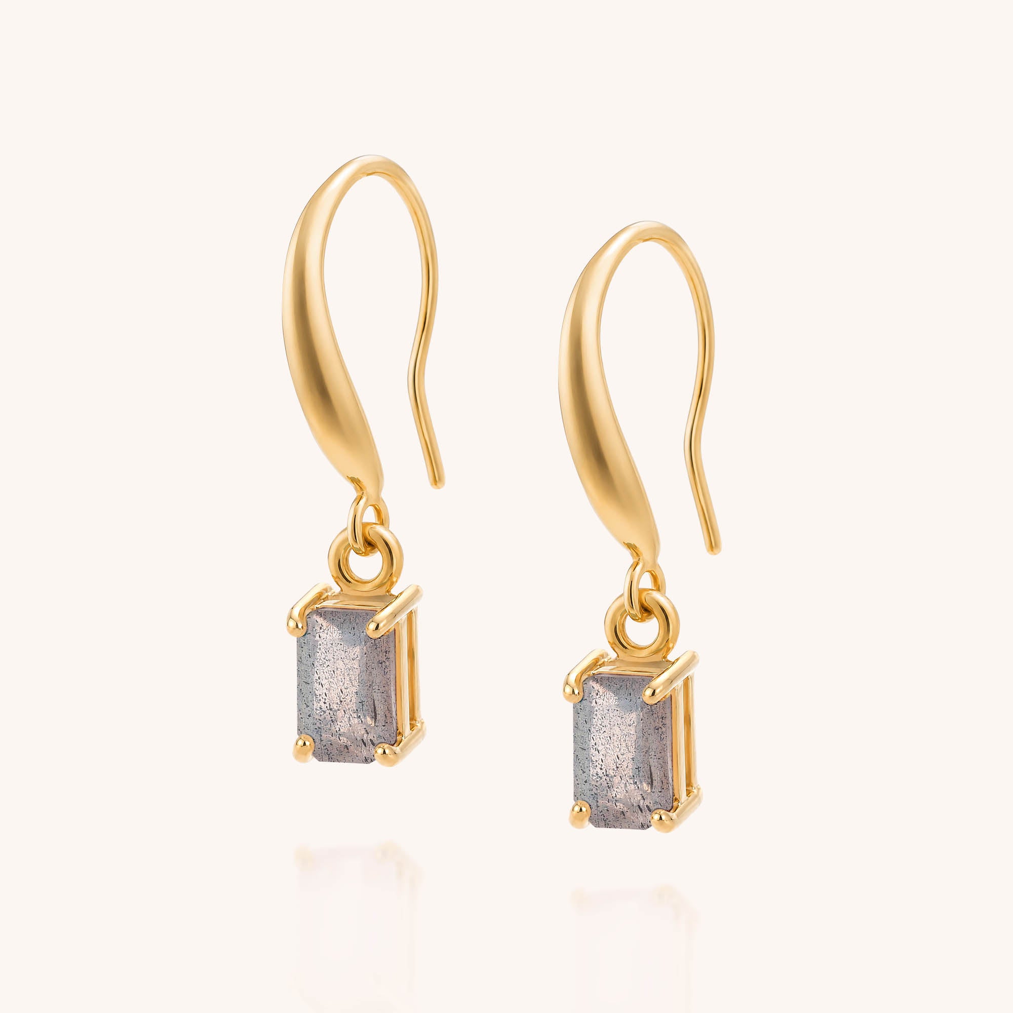 The elegant Labradorite Octavia Drop Earrings feature rectangular gray labradorite gemstones set in gold prongs, beautifully displayed on a plain light background.