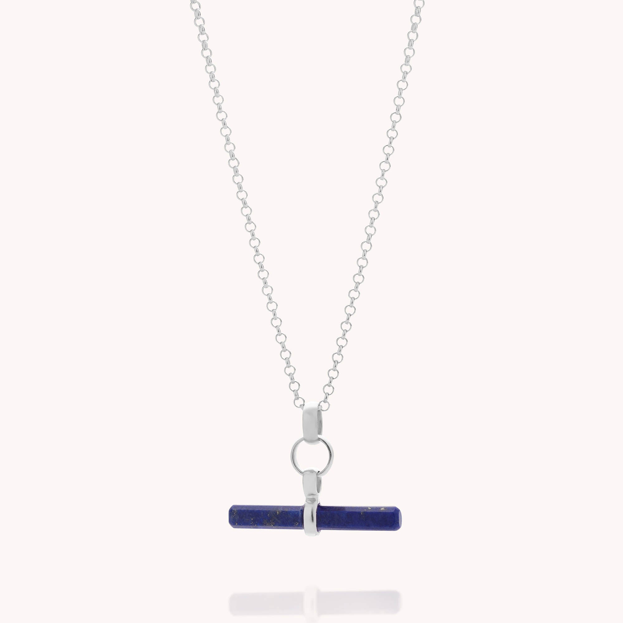 The Gemstone T Bar Necklace features a horizontal cylindrical blue semi-precious stone pendant on a silver chain, secured with metal accents, shown against a plain light background.