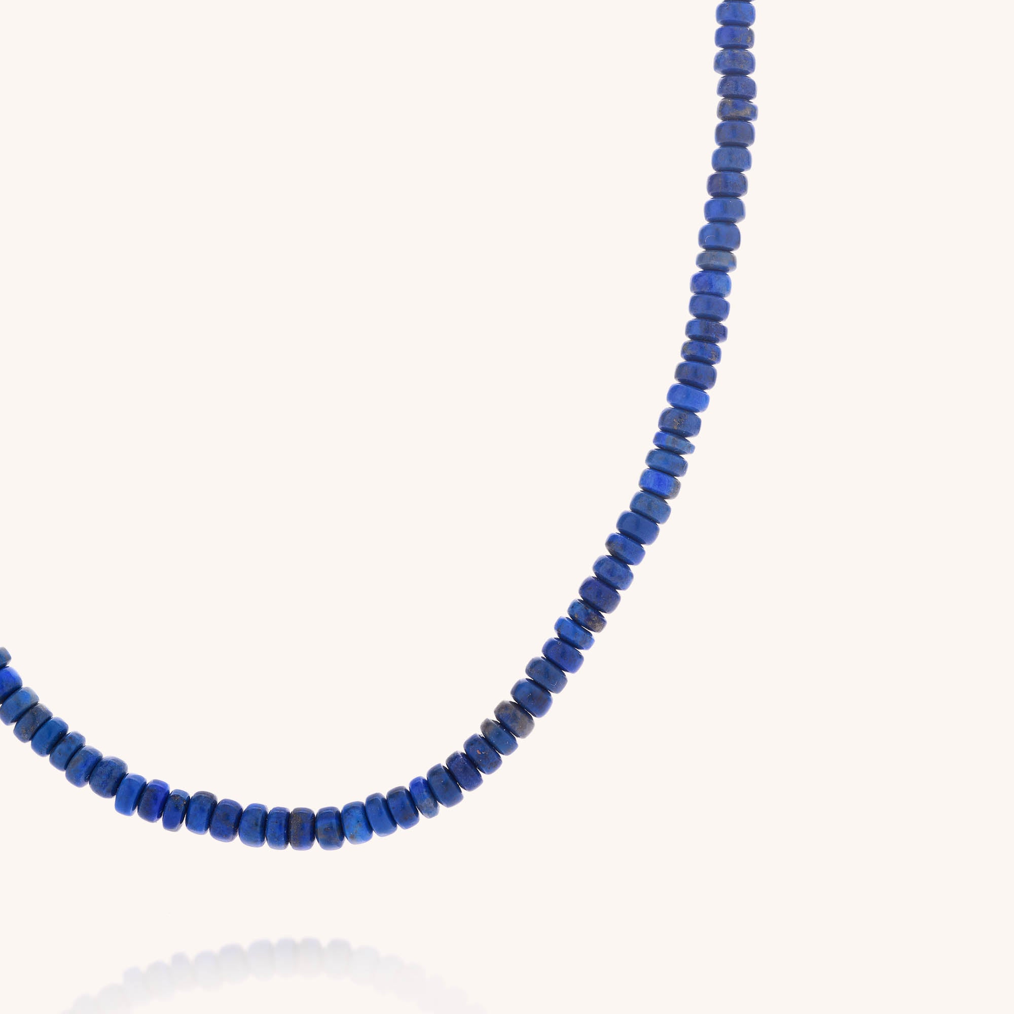 A close-up of the Lapis Lazuli Rondelle Necklace, featuring small, deep blue rondelle beads arranged in a single strand against a simple light background.