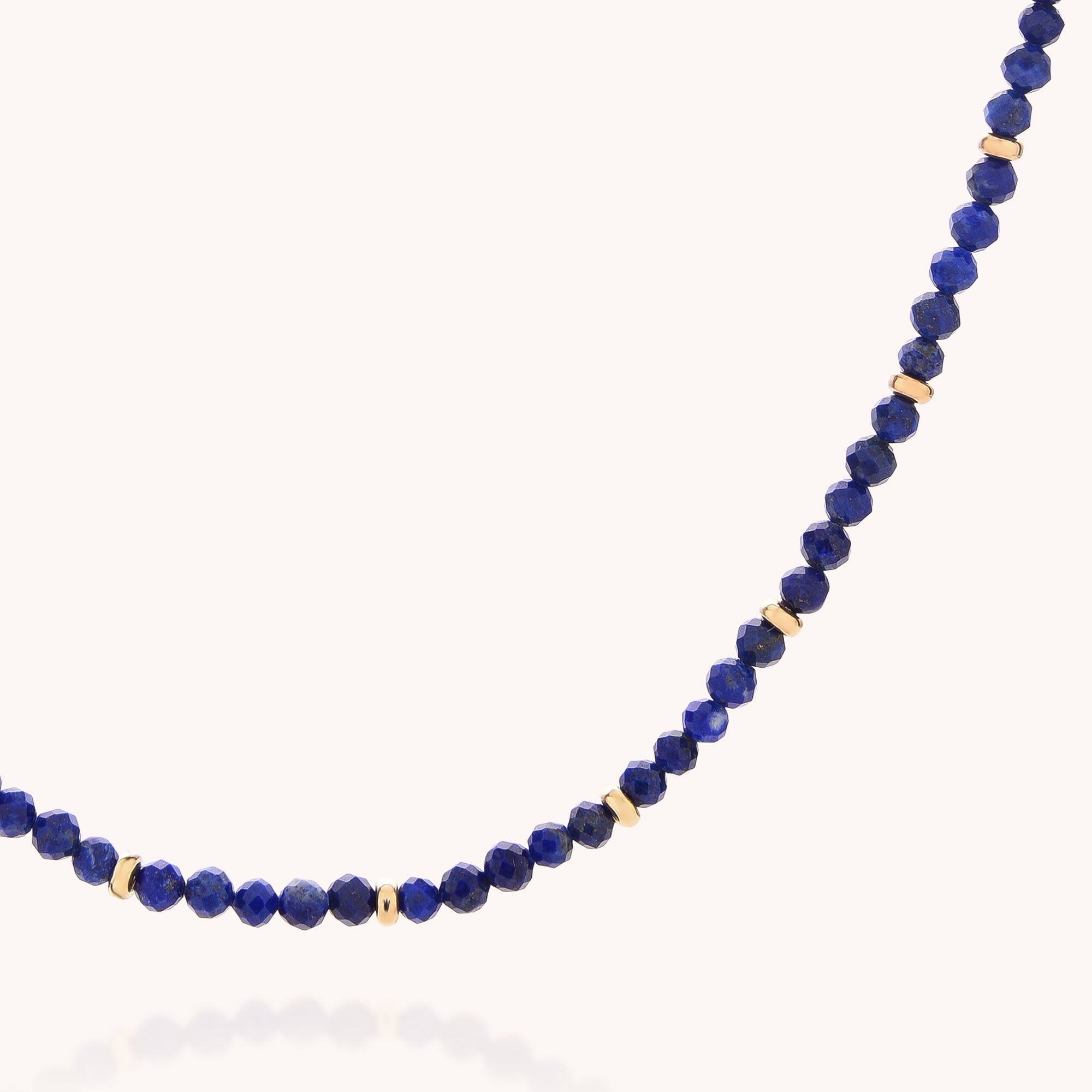Introducing the Lapis September Birthstone Orbit Necklace—a handcrafted jewelry piece featuring deep blue lapis round beads, September’s birthstone, accented with small gold spacer beads and elegantly displayed on a light background.