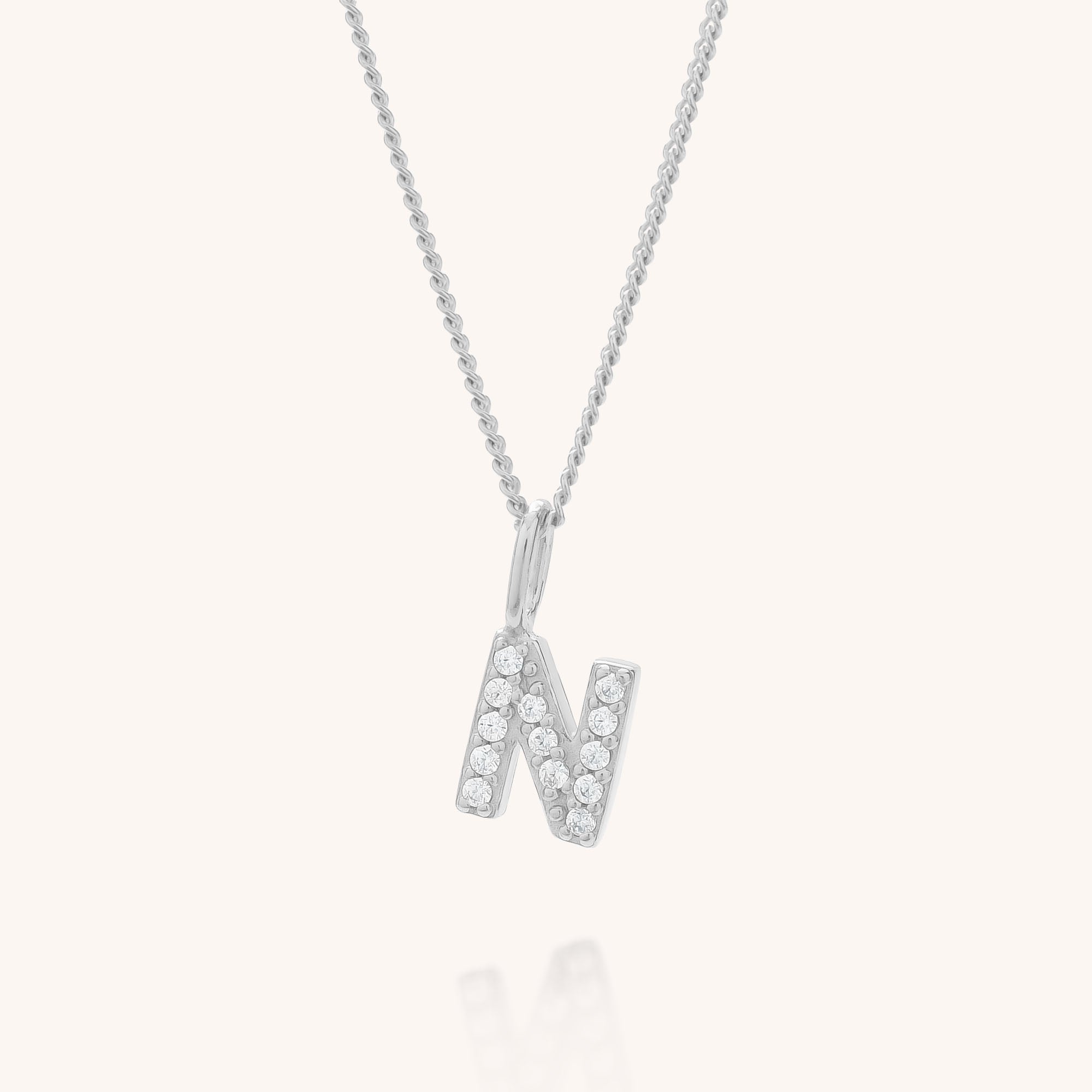 The Initial Sparkle Necklace features a silver pendant shaped like the letter N, adorned with shimmering cubic zirconia stones, shown against a plain white background.