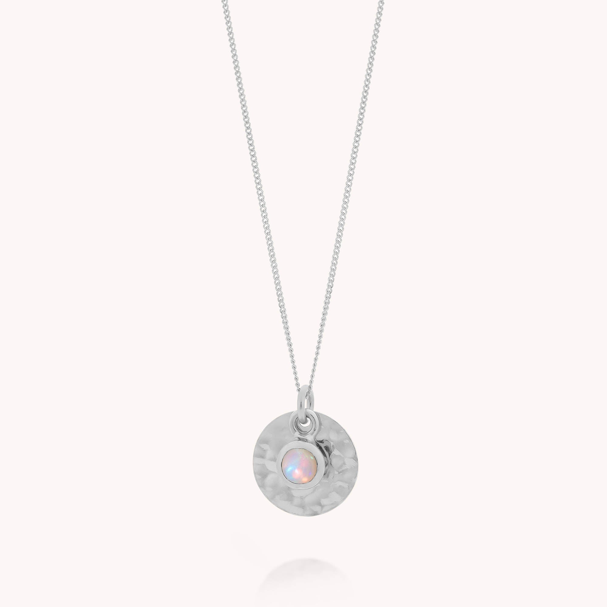 The Ethiopian Opal Luna Disc Necklace features a thin silver chain, a hammered disc pendant, and a central Ethiopian opal—an elegant accessory and perfect October birthstone gift.