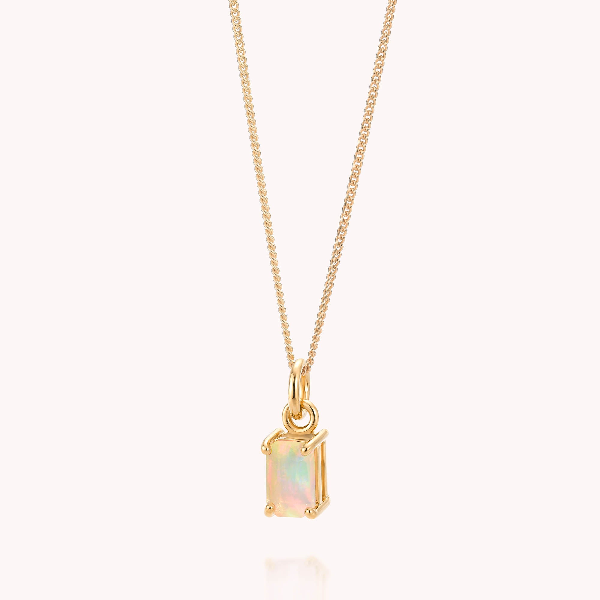 The Opal Octavia Necklace features a gold chain with a rectangular Ethiopian opal pendant set in gold, displayed against a pale background. As the October birthstone, the opal reveals delicate iridescent hues, and its simple yet elegant design makes it a timeless piece.