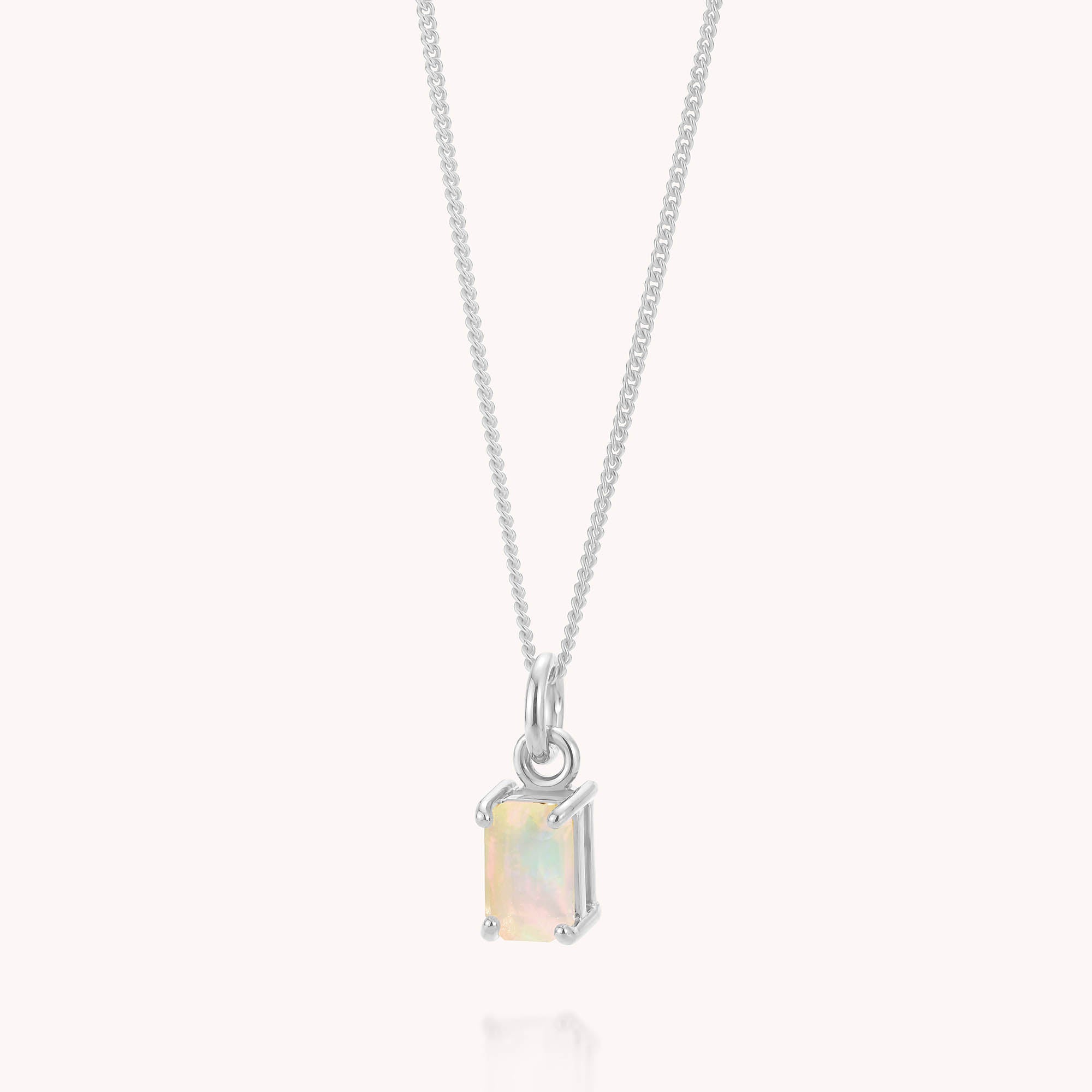 The Opal Octavia Necklace showcases a delicate silver chain with a rectangular, iridescent Ethiopian opal pendant—the ideal October birthstone—set in a minimalist silver prong setting and presented against a plain, light background.