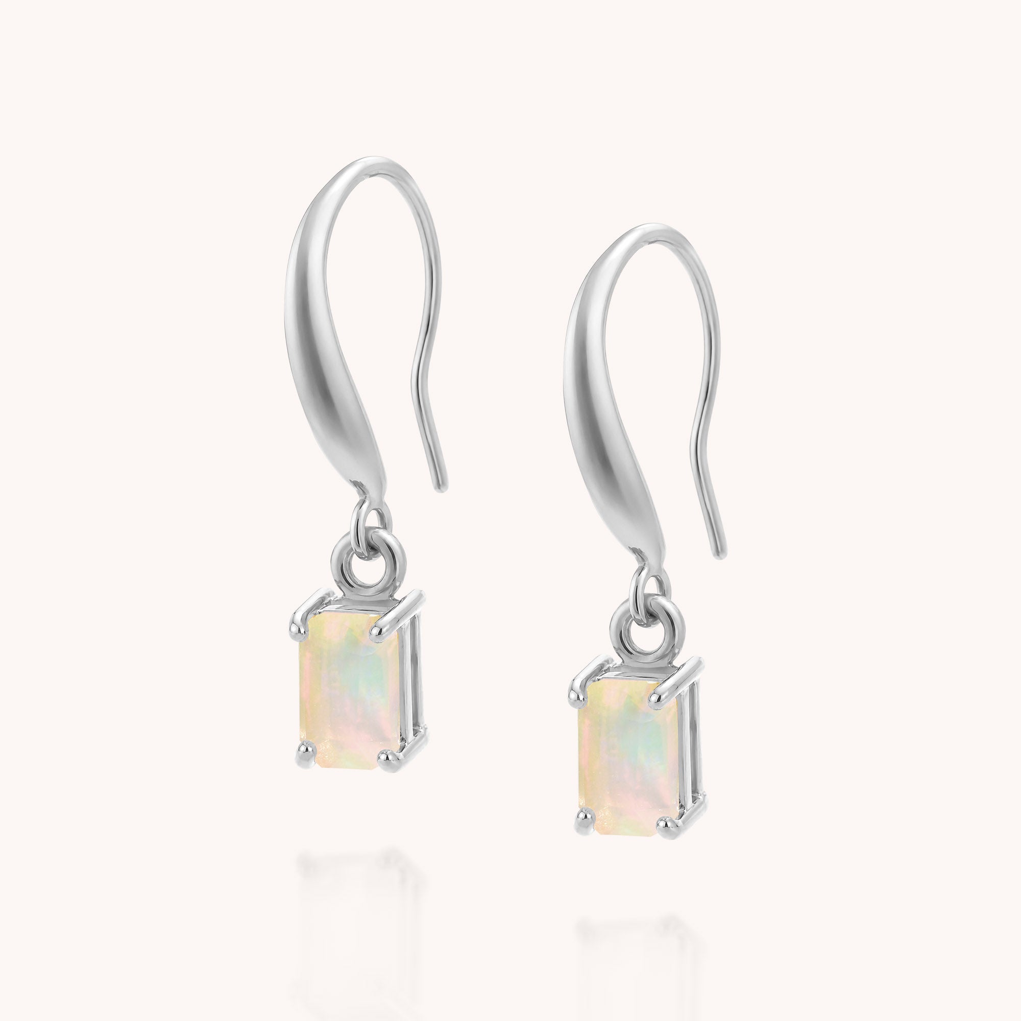 Introducing the Opal Octavia Drop Earrings—a pair of sterling silver drop earrings featuring rectangular pastel Ethiopian opal gemstones set in prongs and elegantly suspended from curved hooks. These refined earrings make a sophisticated statement against a plain white background.