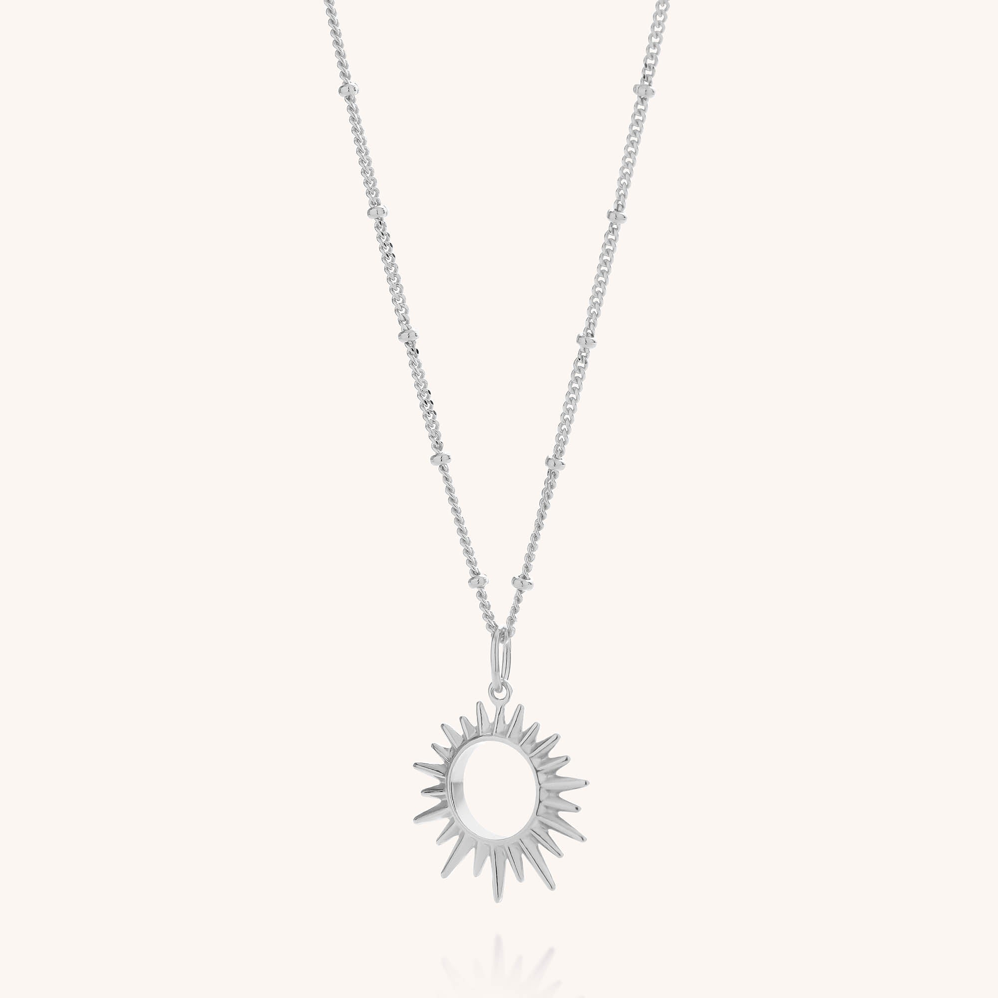 Introducing the Sol Necklace: a beaded chain necklace featuring a sunburst-shaped pendant with pointed rays radiating from an open circular center, beautifully crafted in gold-plated sterling silver and showcased against a clean white background.