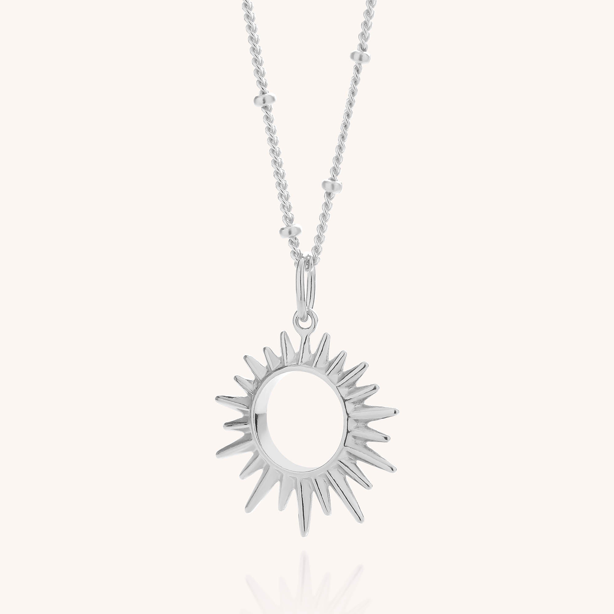 The Sol Necklace is crafted in gold-plated sterling silver, featuring a striking sun-shaped pendant with pointed rays and an open circular center. Displayed elegantly on a light background, this adjustable chain necklace offers both style and versatility.