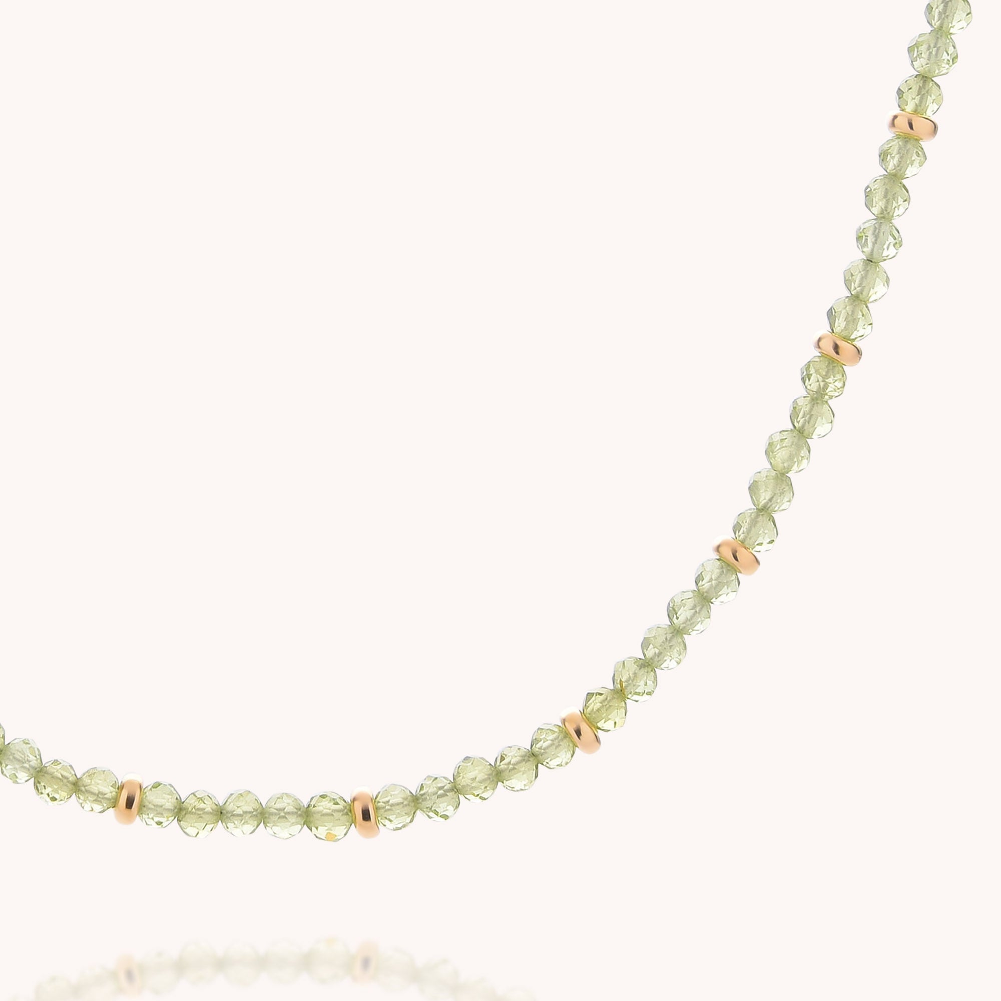 The Peridot August Birthstone Orbit Necklace features light green, faceted peridot beads accented with small gold spacers, all arranged in a single strand against a plain background—an elegant celebration of the August birthstone.