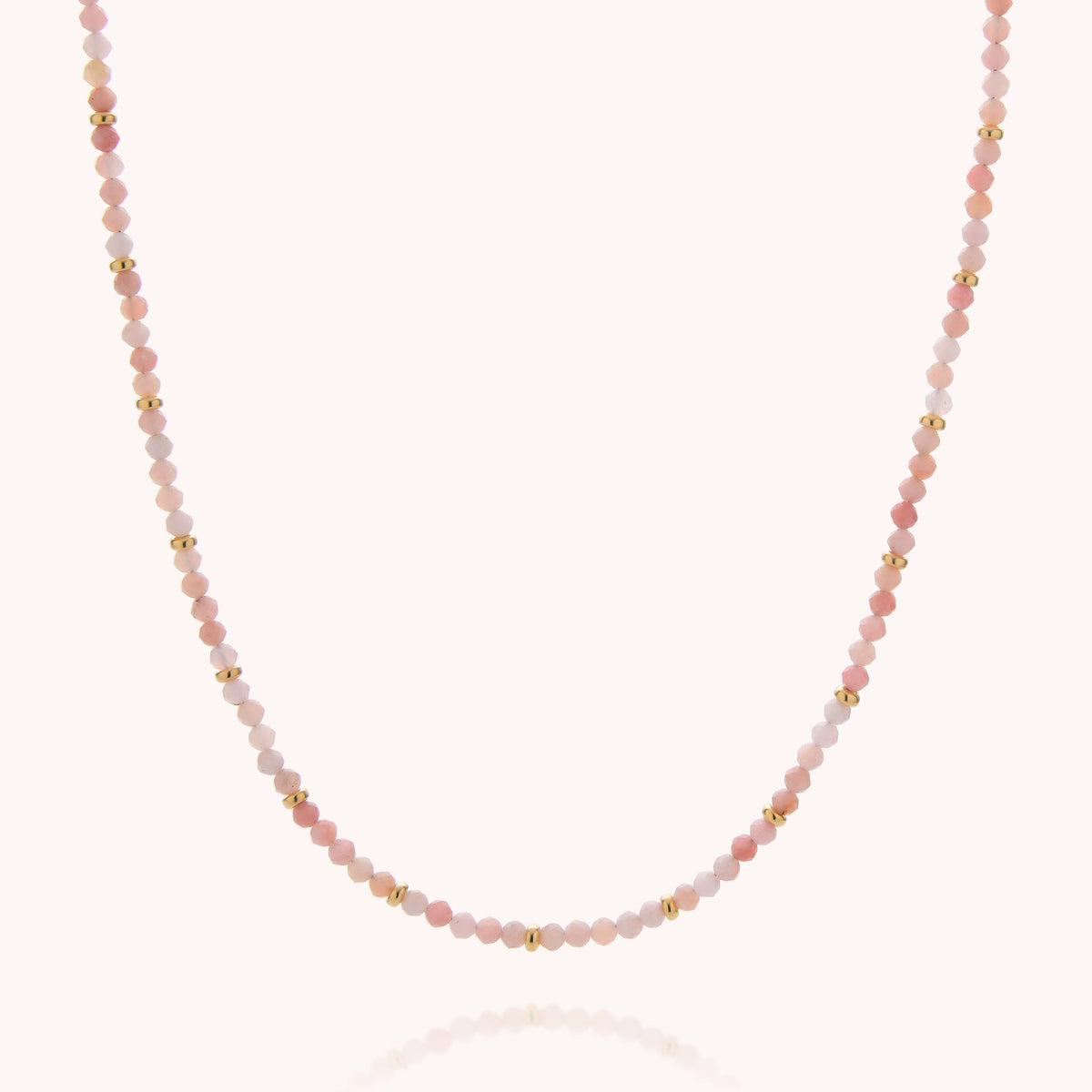 The Pink Opal October Birthstone Orbit Necklace features expertly handcrafted alternating small pink, peach, and gold beads in a simple, elegant pattern against a light background—making it the perfect accessory for an October birthday.
