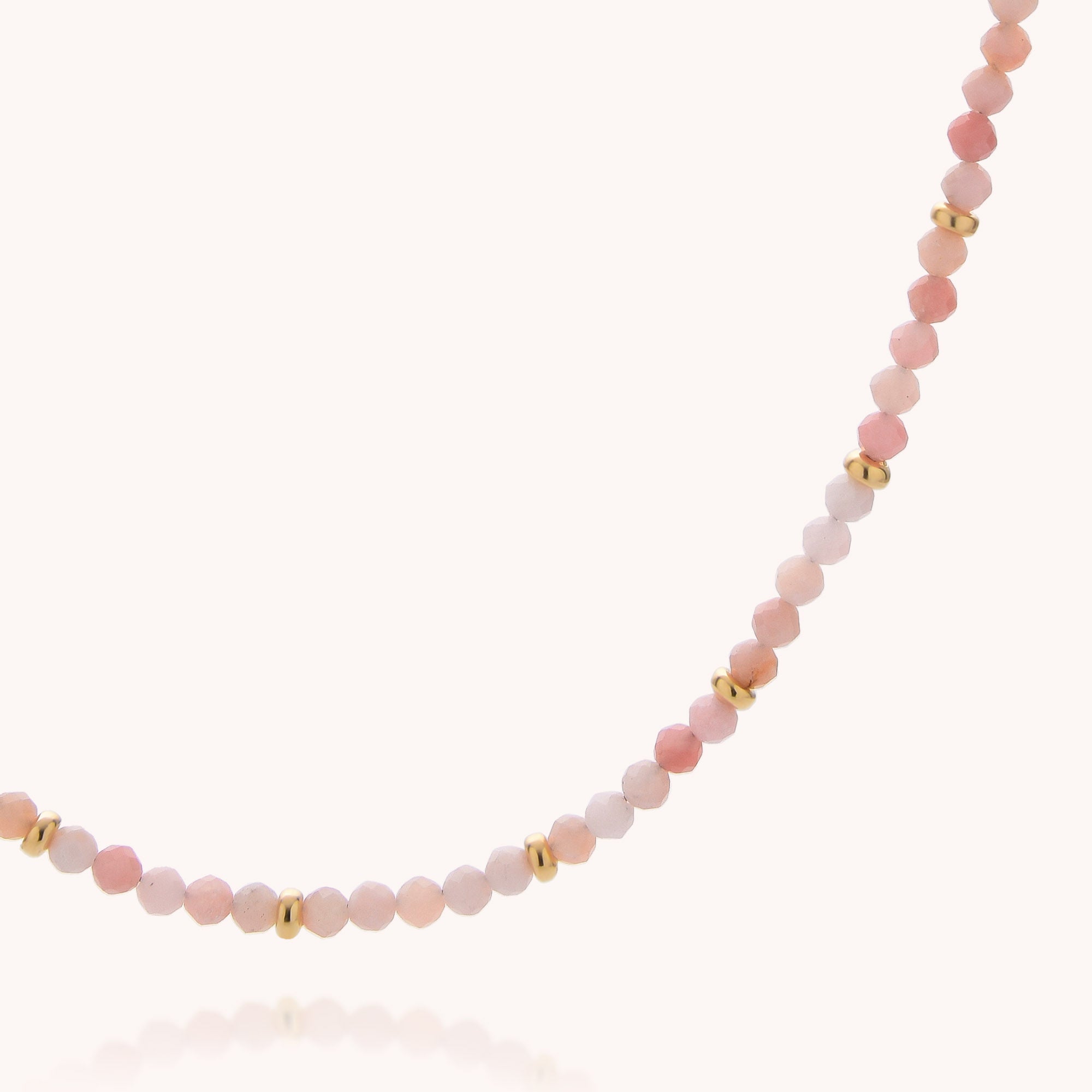 The Pink Opal October Birthstone Orbit Necklace is a delicate handcrafted piece, adorned with small round beads in soft pink shades and accented with spaced gold details. Displayed on a plain white background, this elegant necklace makes a perfect choice for anyone celebrating an October birthstone.