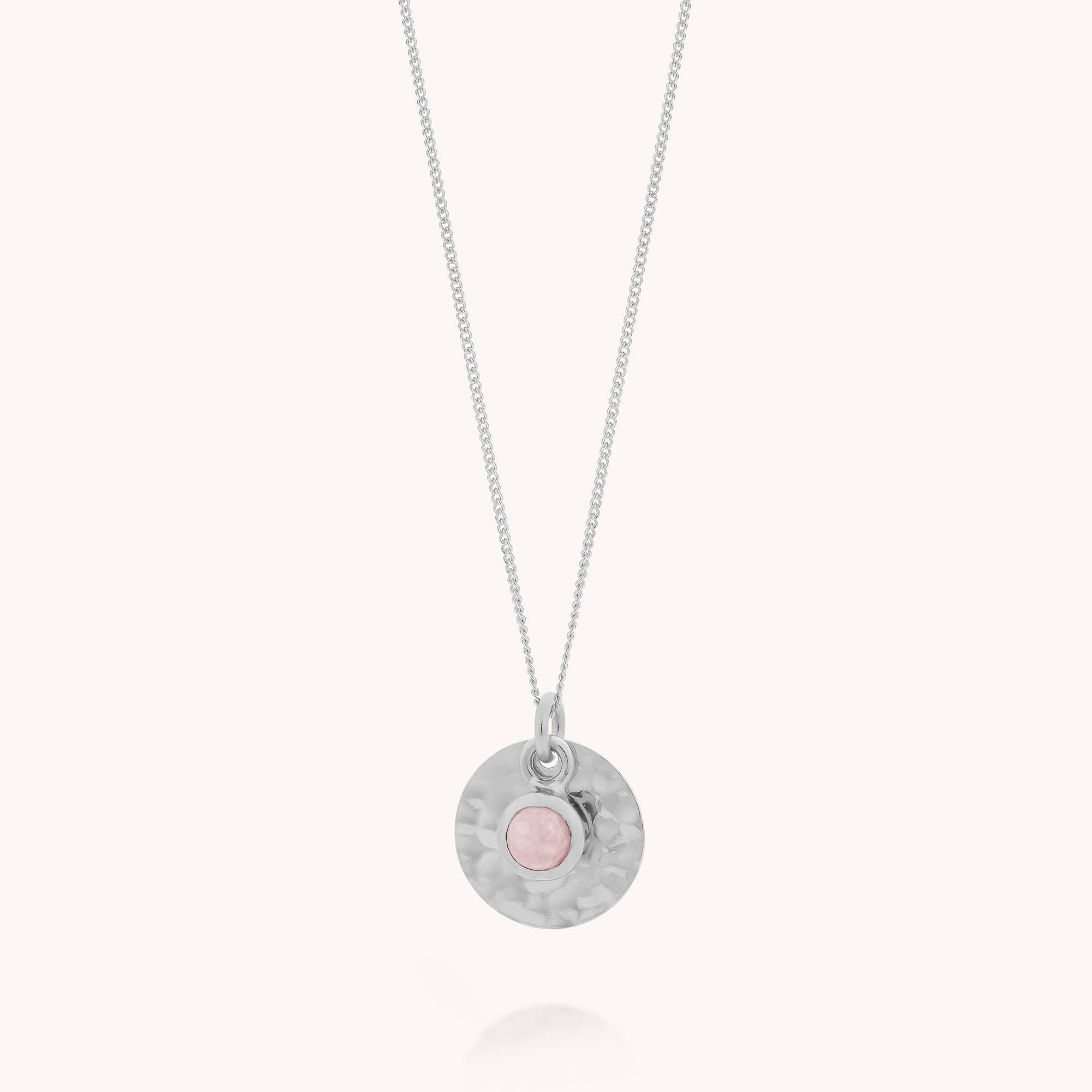 The Rose Quartz Luna Disc Necklace features a delicate sterling silver chain with a hammered disc pendant and a central pink rose quartz gemstone—offering a modern twist on the classic rose quartz necklace.