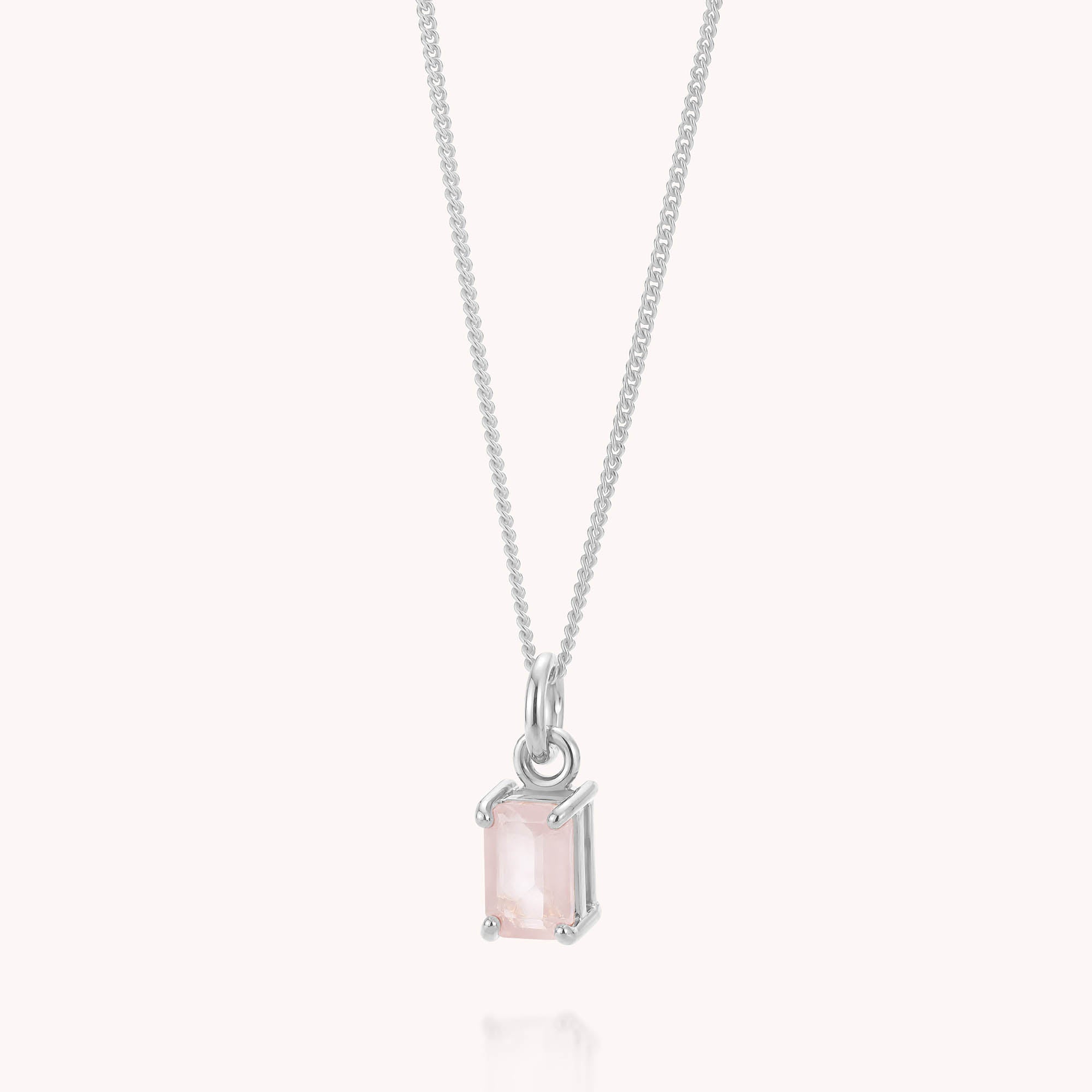 The Rose Quartz Octavia Necklace is a delicate sterling silver piece featuring a rectangular, light pink rose quartz gemstone pendant in a simple four-prong setting, beautifully displayed against a plain, light background.