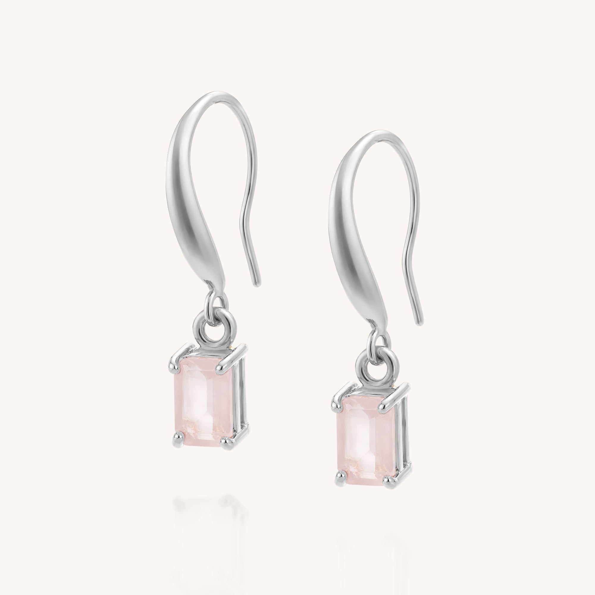 The Rose Quartz Octavia Drop Earrings are sterling silver hook drop earrings featuring rectangular, pale pink rose quartz stones set in prongs and displayed on a plain white background.