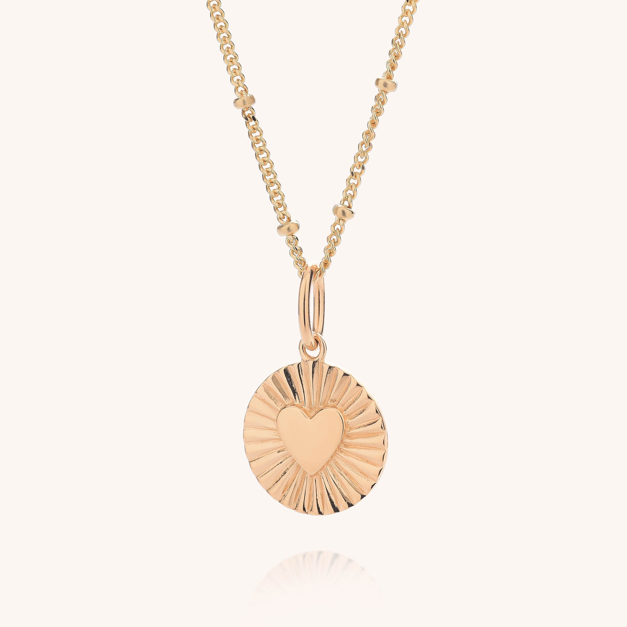 Shining Heart Necklace Sterling Silver with a round, textured pendant featuring a raised heart at the center, displayed on a simple beaded sterling silver chain against a light background.