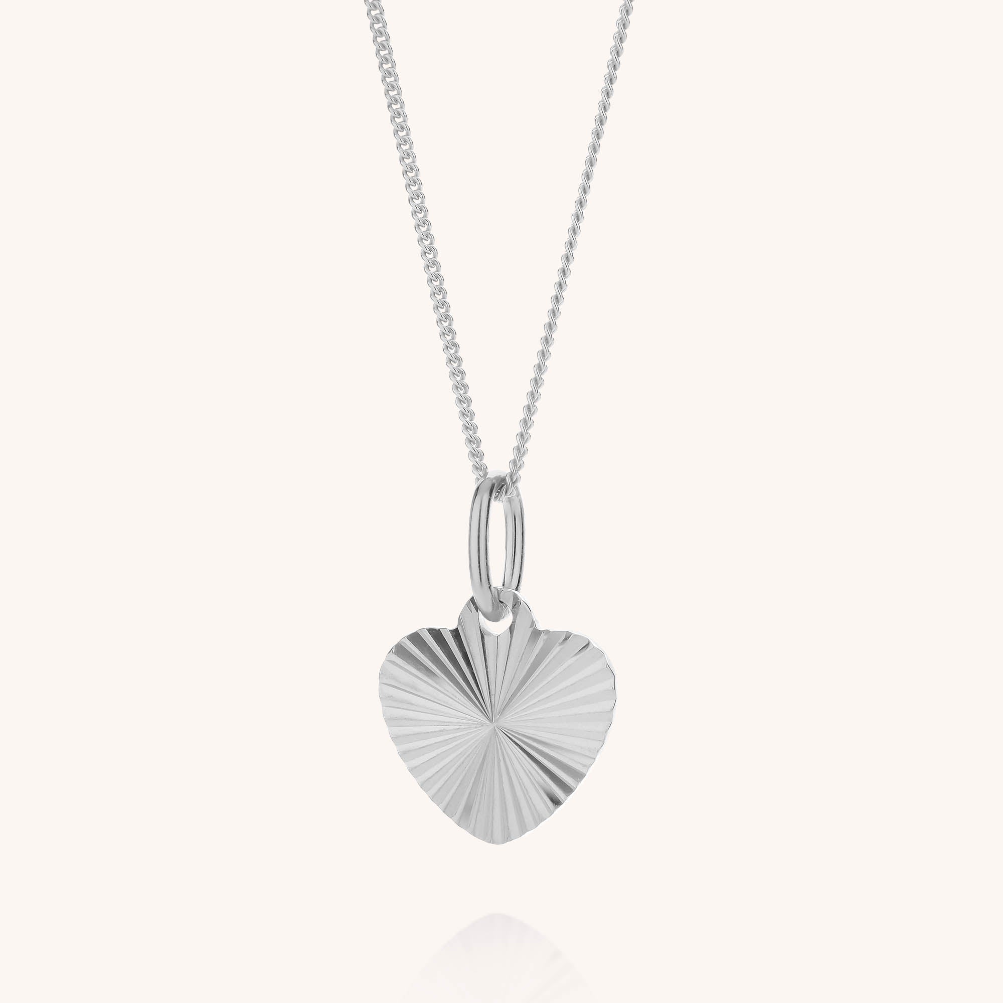 The Celeste Heart Necklace features a textured, radiating silver heart-shaped pendant suspended from a delicate sterling silver chain, displayed against a plain white background.