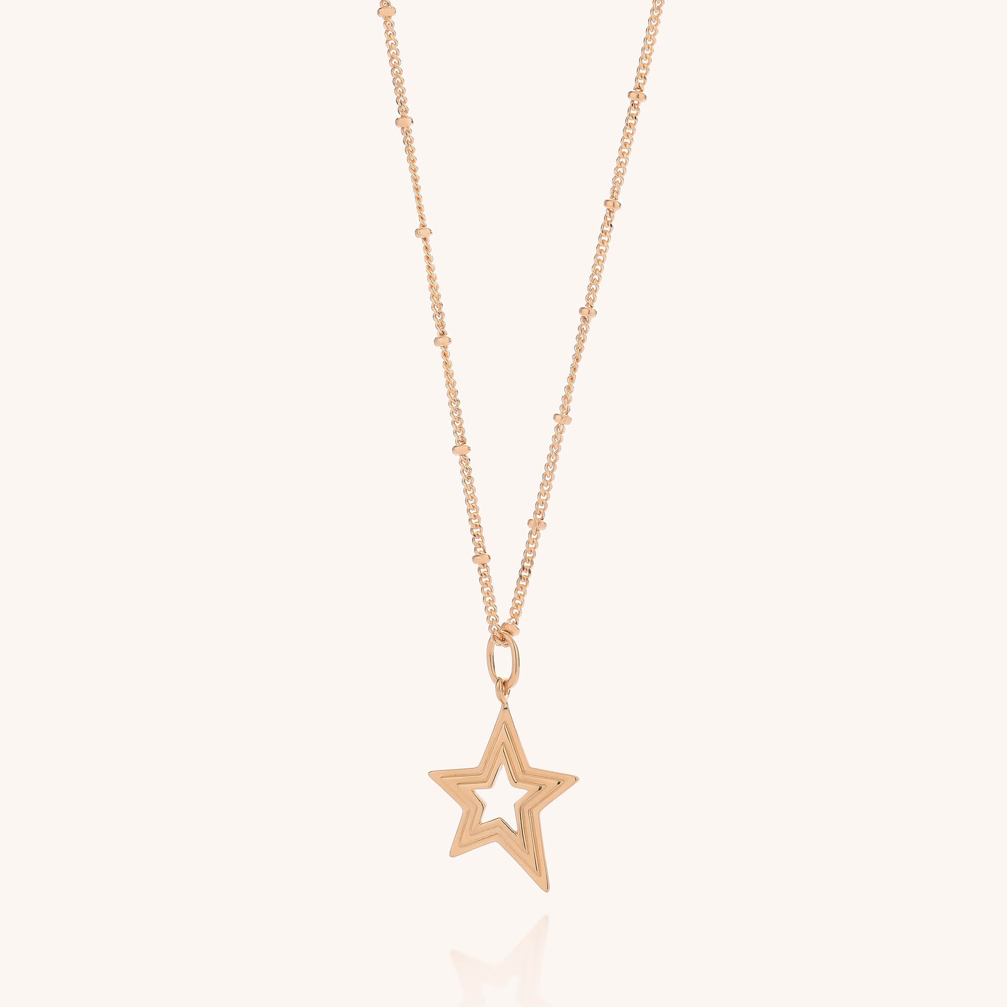 Delicate gold necklace featuring a fine chain adorned with small beads and a distinctive star-shaped pendant with an open center, echoing the layered star motif—styled simply against a light background. If you adore celestial-inspired jewelry, discover our Stellar Starburst Necklace or browse our sterling silver collections for comparable designs.