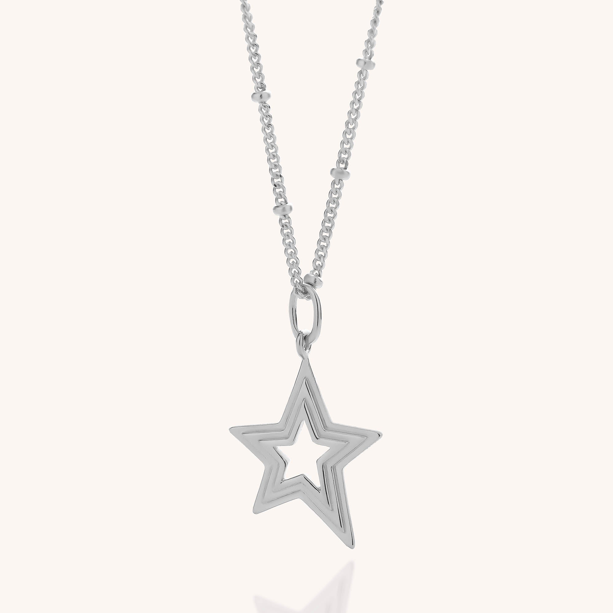 Stellar Starburst Necklace in sterling silver, featuring a delicate beaded chain and a star-shaped pendant with a cut-out star outline, reminiscent of a Starburst Necklace, displayed on a plain light background.
