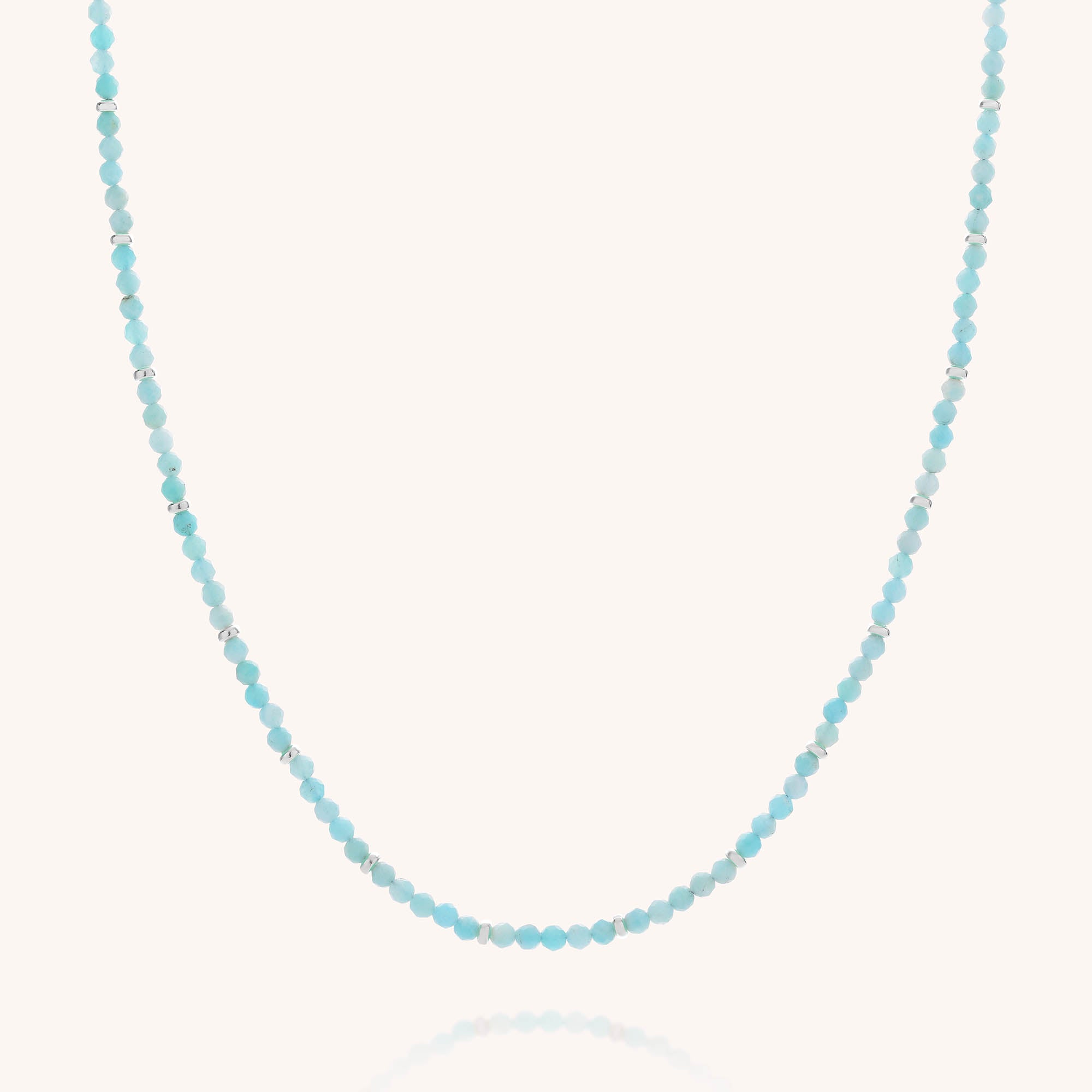 The Amazonite Orbit Necklace features small, round faceted amazonite beads in various shades of light blue, evenly spaced along a thin, nearly invisible gold plated sterling silver string and beautifully displayed against a white background.