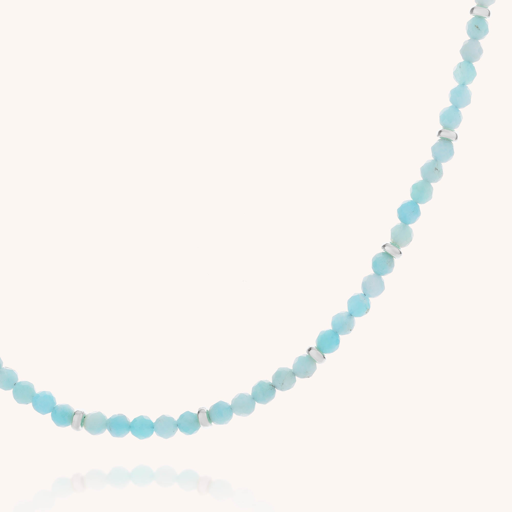 Introducing the Amazonite Orbit Necklace, a delicate single-strand necklace crafted with small, faceted light blue amazonite beads and accented by occasional gold-plated sterling silver spacer beads, beautifully displayed against a white background.