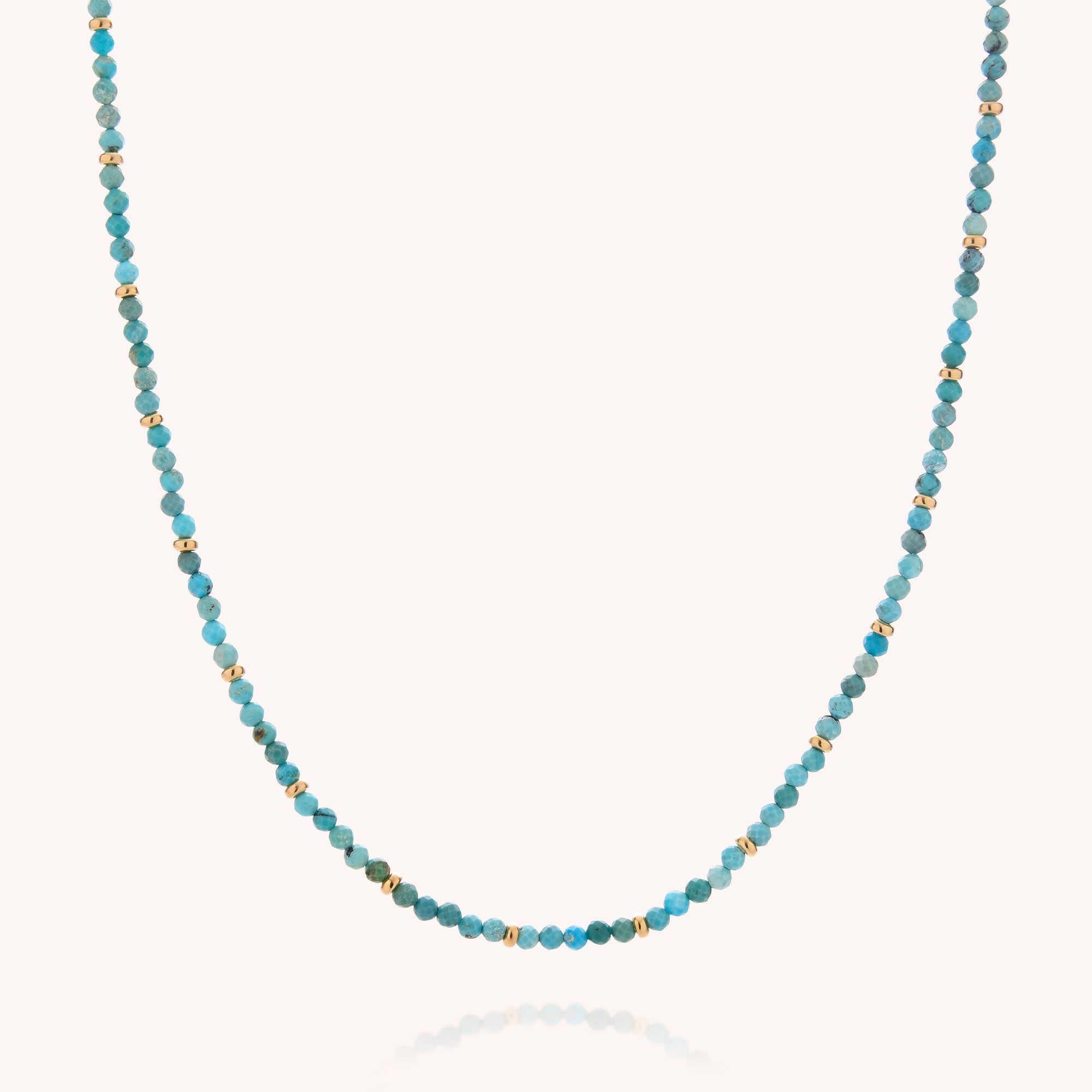 The Turquoise December Birthstone Orbit Necklace is a delicate handcrafted piece featuring small round turquoise beads, evenly spaced with tiny gold beads, beautifully displayed on a plain light background.