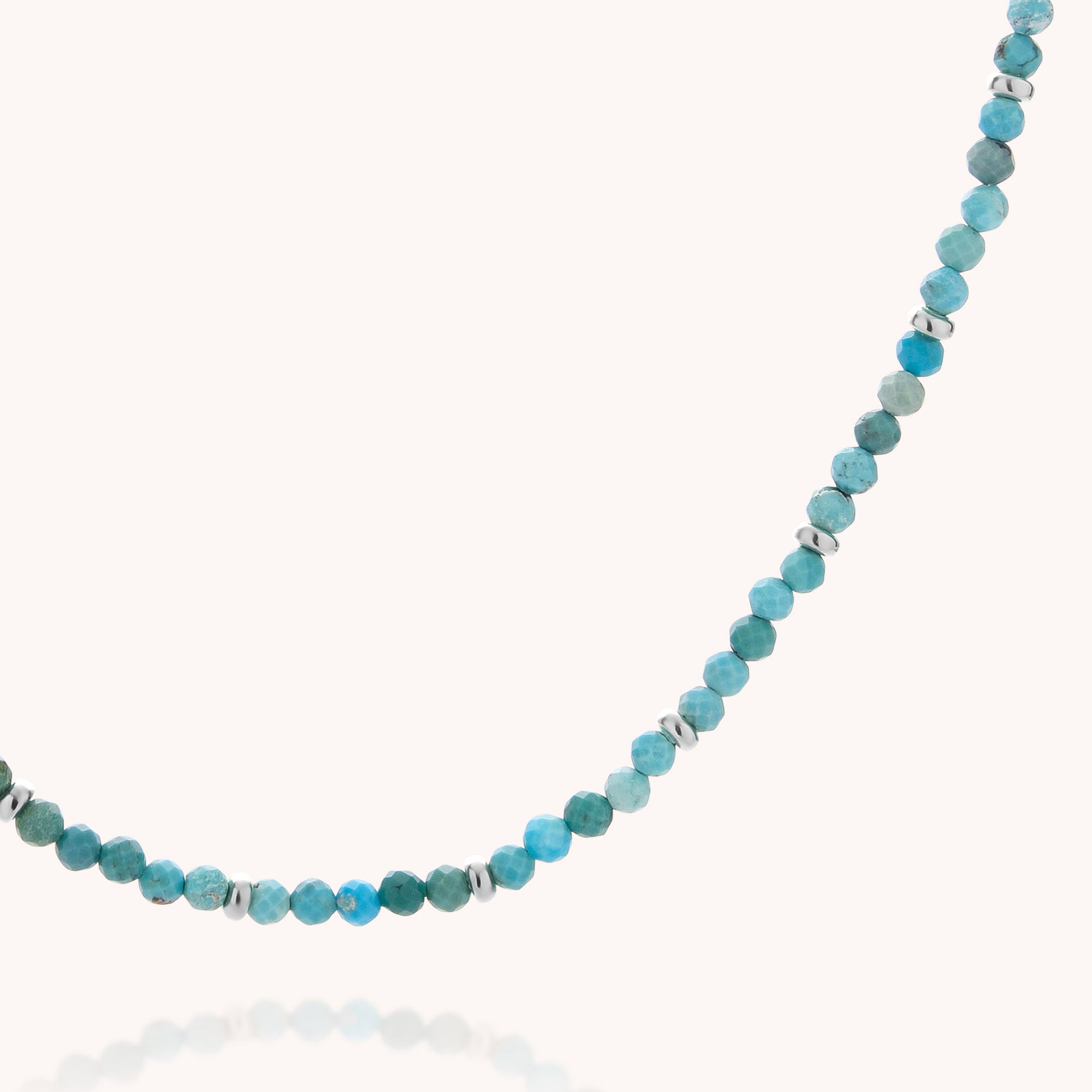 A close-up of the Turquoise December Birthstone Orbit Necklace, featuring small, round turquoise beads—December’s birthstone—accented with silver spacer beads and displayed on a white background.