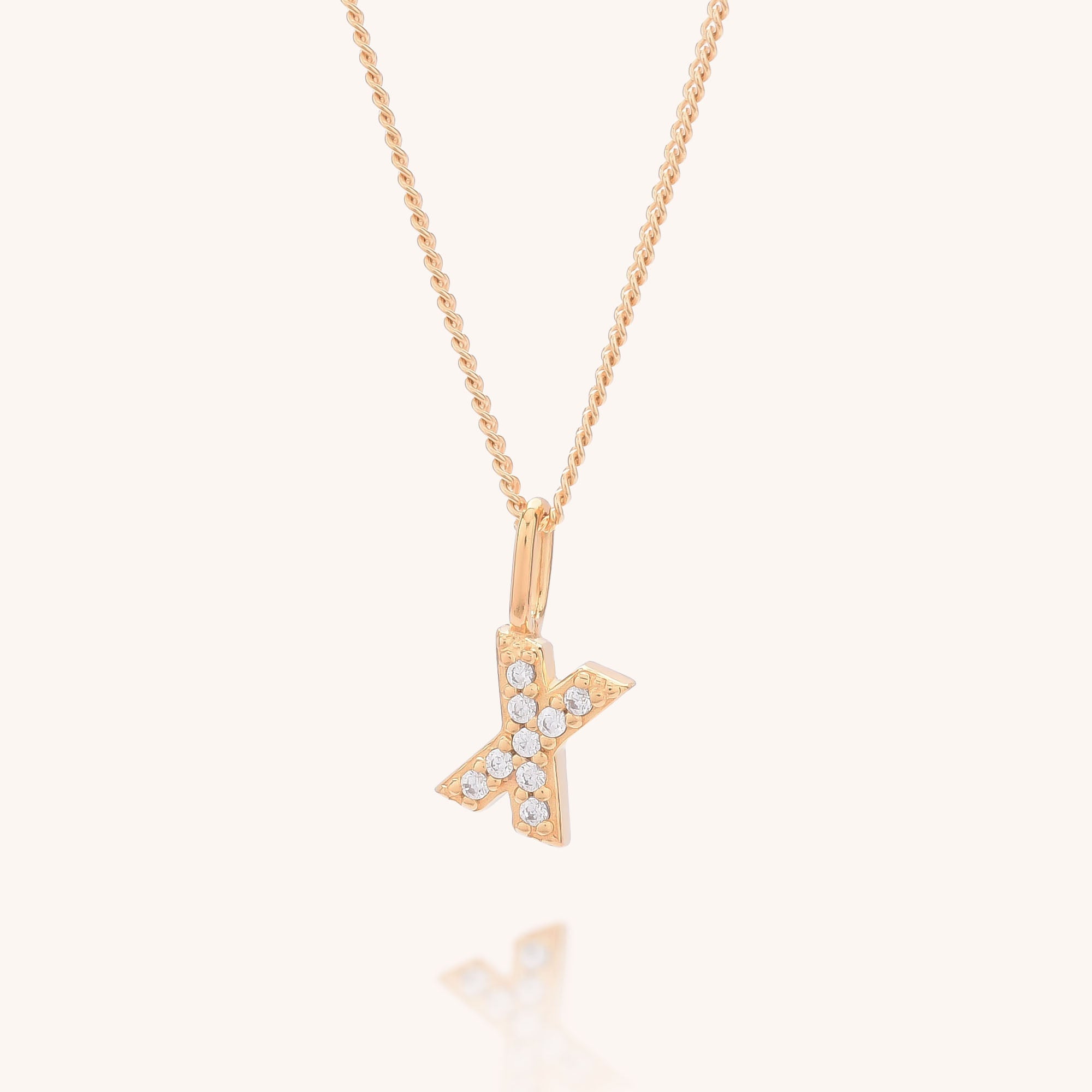 The Initial Sparkle Necklace is a gold chain with a K-shaped pendant adorned with sparkling cubic zirconia, shown against a plain light background.