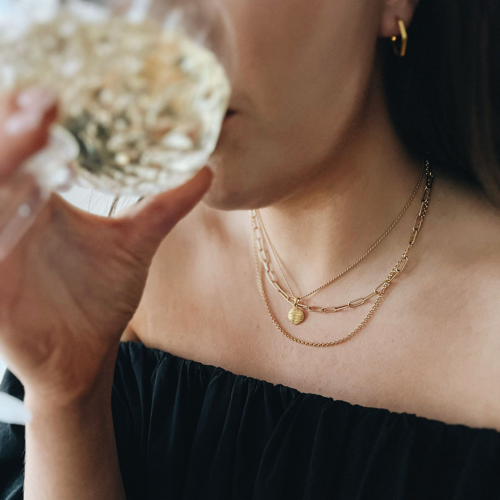 lady drinking from a glass wearing gold necklace chain for woman