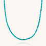 The Mini Bead Necklace features small, round turquoise gemstones evenly strung together with a sterling silver clasp, creating a simple and elegant loop displayed against a plain white background.